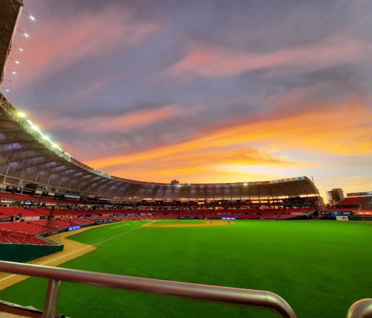 A vibrant stadium with a sunset-lit sky.