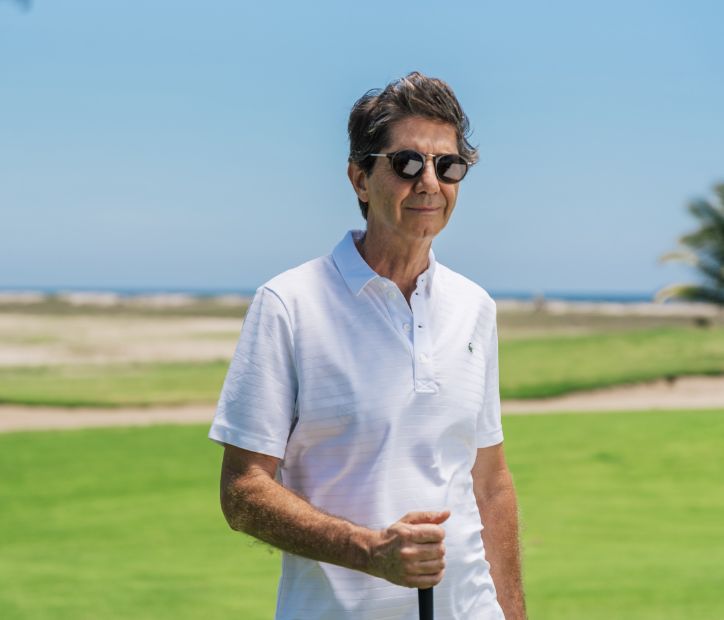 A man in sunglasses and a polo shirt stands on a lush golf course in Mazatlán.