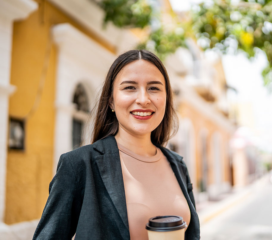 A smiling professional woman in business attire enjoying a coffee in Mazatlán’s historic district.