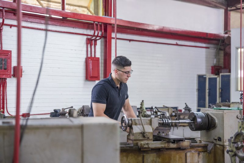 Manufacturing worker operating machinery in a Mazatlán facility, highlighting cost-effective labor solutions.