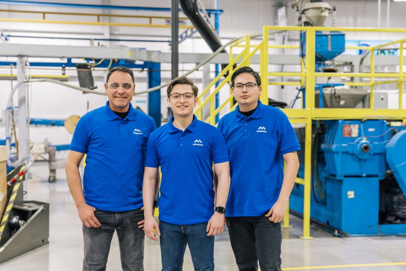 Three Tetakawi employees standing inside a Mazatlán manufacturing facility, representing a stable and skilled workforce in Mexico.