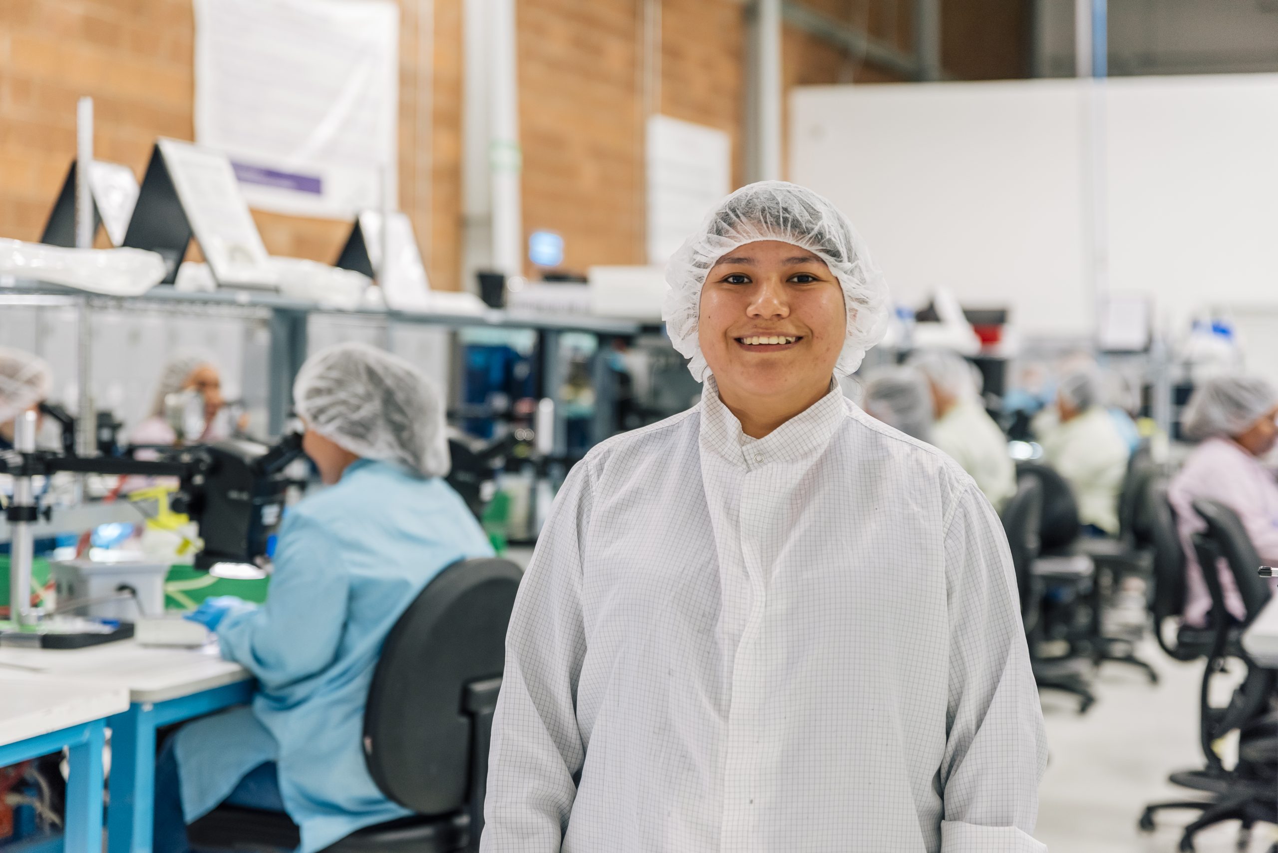 Smiling operator in cleanroom attire at a medical device manufacturing facility in Mexico